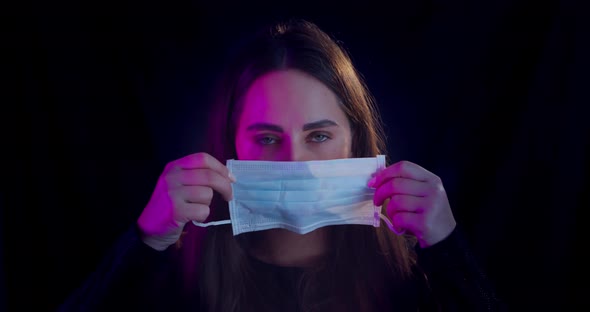 A Girl in a Protective Medical Mask. Studio Shot on a Black Background. Quarantine, Fears