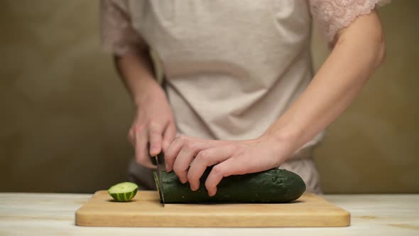 Woman slicing cucumber on kitchen board