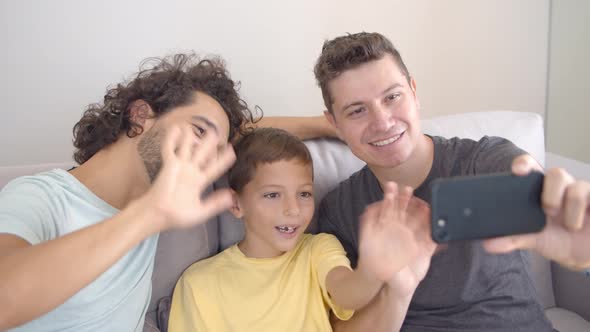 Cheerful Gay Parents and Kid Using Cell Phone for Video Call