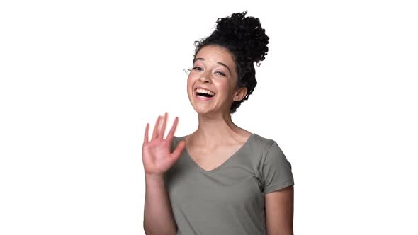 Portrait of Hospitable Woman with Tied Hair in Bun Smiling on Camera and Greeting with Waving Hand