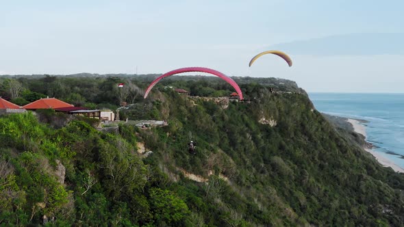 Aerial Drone Flight Over The South Coast At Sunset, Bali, Indonesia, Two Paragliders Flying To Each