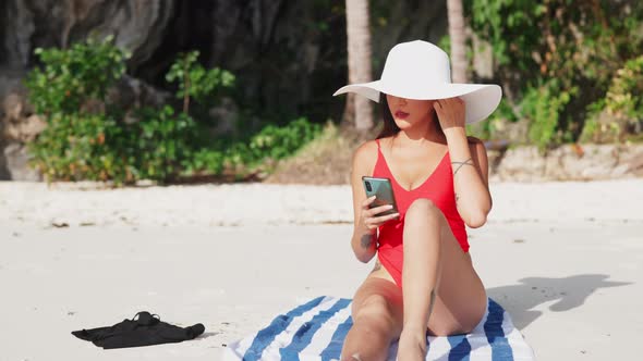 Young Woman Sitting On Beach With Smartphone