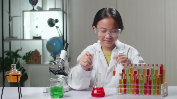 Young Asian Scientist Girl Mixes Chemicals In Test Tube. Child Learn With Interest