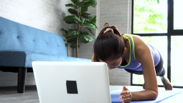 Asian Woman in Sportswear Doing Plank Poses While Watching Fitness Training Class on Computer Online