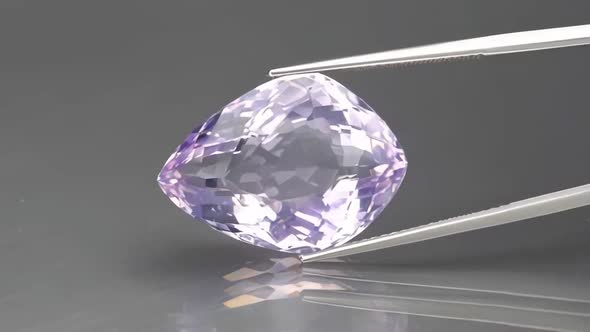 Natural Amethyst Fantasy Cut in the Tweezers on the Background