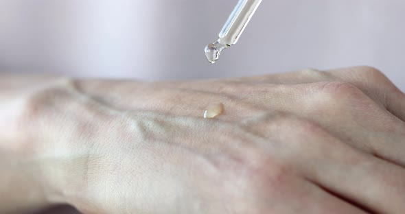 Woman Hand Applies Liquid Serum From Pipette to Skin to Moisturize Skin