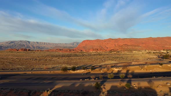 Rising view of a road with passing cars in the desert in a quiet valley and mountains at sunset