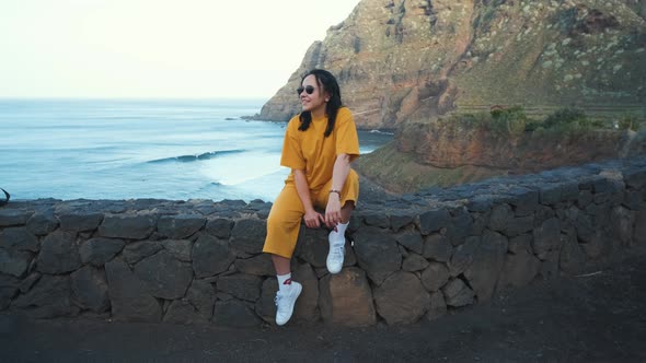 A Woman Walks Next to the Ocean Enjoying the Calm Scenery Against the Background of the Volcanic