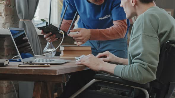 Volunteer Doing Wi-Fi Router Setup for Man with Disability