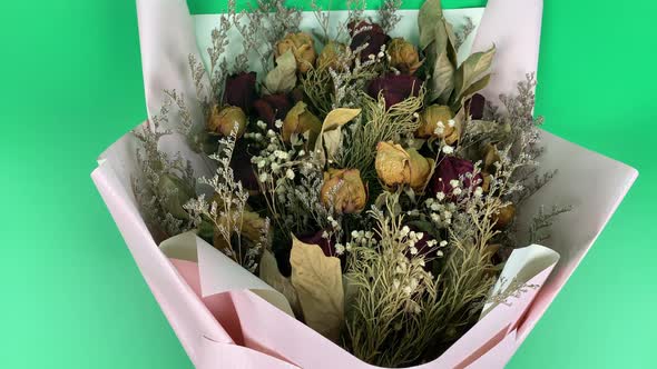 Romantic composition of dried flowers. Dried roses in slow motion on a green background.