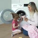 Mother with Little Smiling Daughter Sit on Floor and Put Soft Toys for Washing - VideoHive Item for Sale