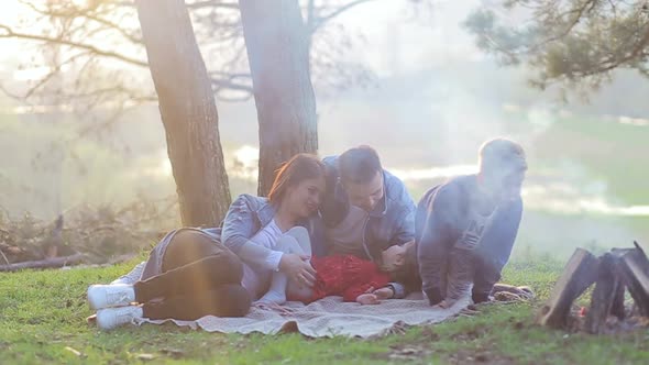 Happy family concept. Young mother and father kissing their daughter in the park.