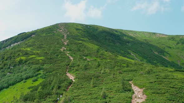 Aerial View of a Young Couple Walking Along a Mountain Trail to the Top of the Mountain