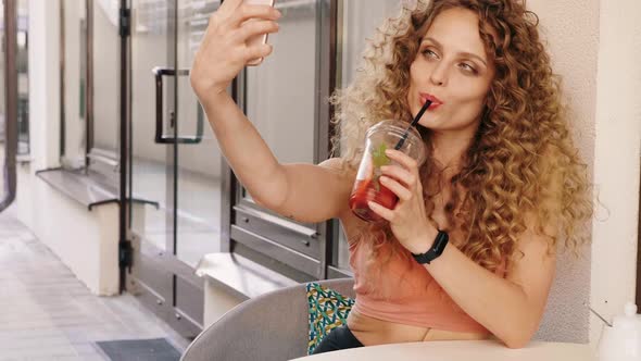 Woman in summer trendy clothes sitting in veranda cafe