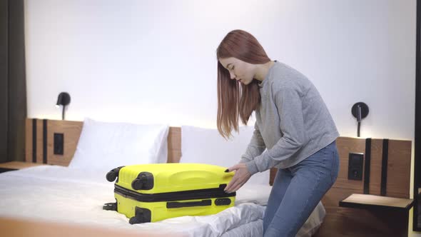 Beautiful Teenage Girl Closing Yellow Travel Bag. Portrait of Confident Caucasian Teenager Packing