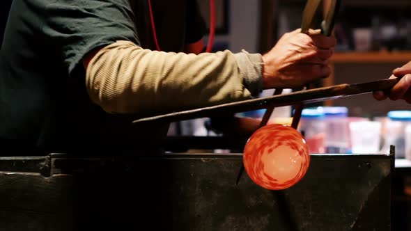 Team of glassblowers shaping a molten glass