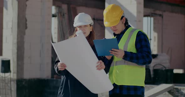 Supervisor Holding Blueprint While Discussing with Worker