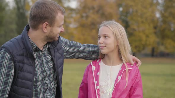 Portrait of Caucasian Father and His Blonde Daughter Hugging in the Autumn Park