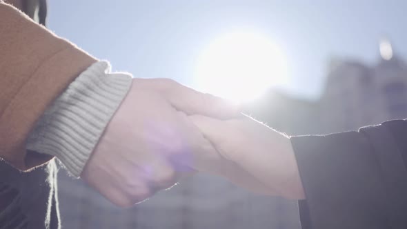 Man and Woman Hands Close Up in Front of Urban Cityscape. The Man Holding Hands of His Girlfriend