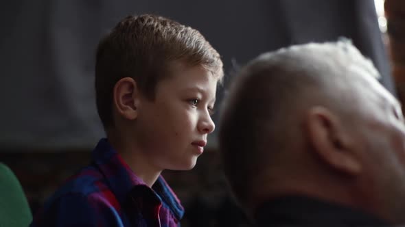 Closeup of Grandfather Talking To Grandson at Home Sitting in Cozy Dark Living Room