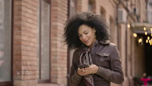 Portrait of Young African American Woman Dancing and Enjoying Music with Wireless Headphones Using