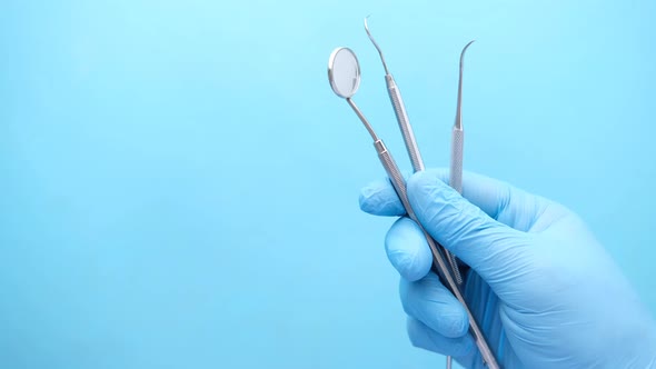 Hand in Latex Gloves Holding Dental Equipment