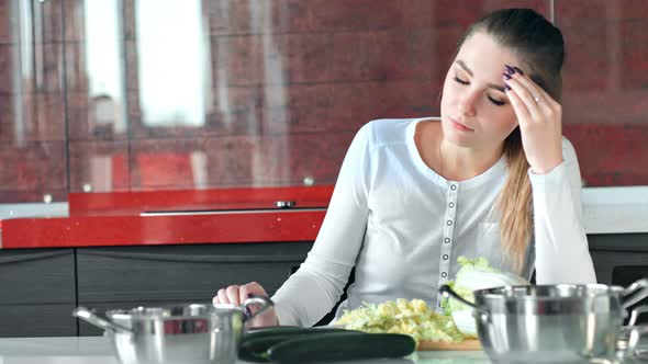 Pretty Young Housewife is Tired Cooking Salad in the Kitchen