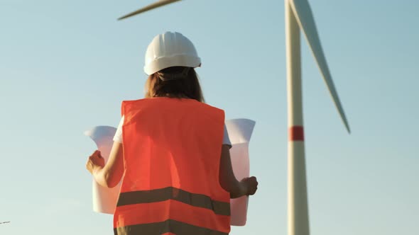 Woman Engineer Takes Off Her Helmet After Work at the Station with Windmills