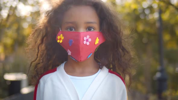 Portrait of Small African Girl with Face Mask Standing Outdoors