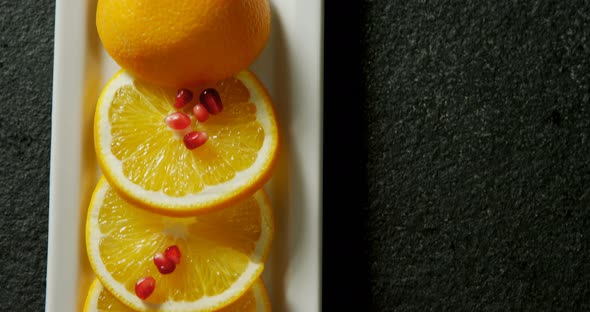Slice of orange with pomegranate seeds in tray on black background 4K 4k