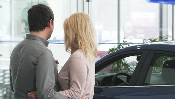 Rearview Shot of a Mature Couple Examining a New Car at the Dealership