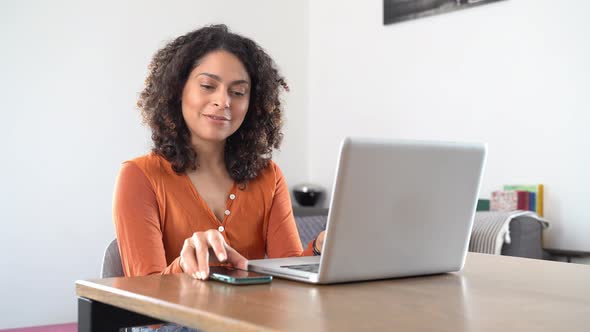 Smiling woman working in her home office, using smartphone