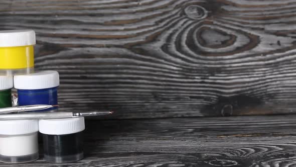 A Set Of Gouache And Brushes. Jars Of Paint Stand In A Pyramid.  Slider Camera. On Pine Boards.