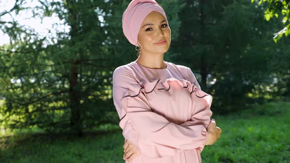 Woman in a Beautiful Turban and a Dress of the Same Color Against the Background of a Fir Tree