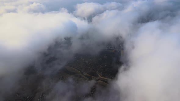 Aerial View From High Altitude of Distant City Covered with Puffy Cumulus Clouds Forming Before