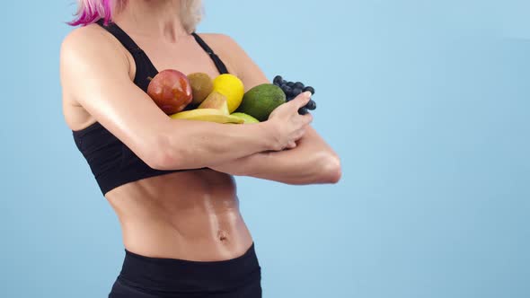 Sports Woman Holds a Lot of Fruit in Hands the Studio Close Up