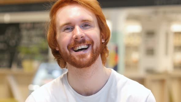 Portrait of Redhead Beard Man Laughing on Joke in Cafe