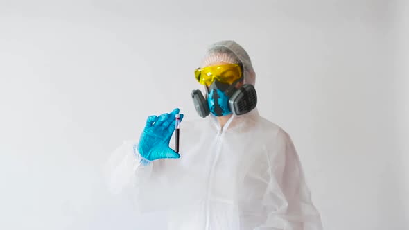 Doctor in a White Protective Suit and Respirator Shows a Blood Sample in a Test Tube. Focus on the