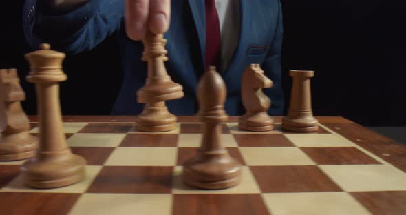 Hand of Businessman Thinking To Moving White Bishop Chess Figure in Competition