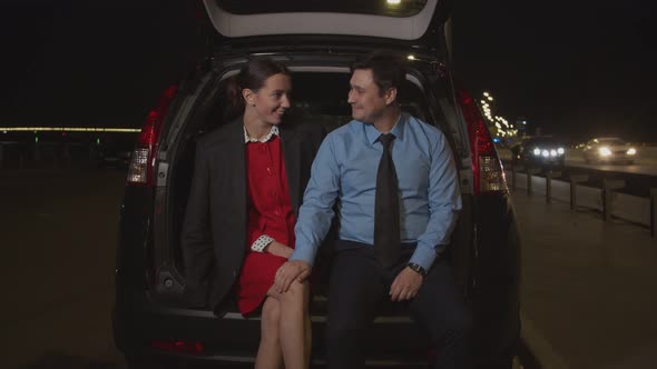 Man Flirting with Businesswoman in Car at Night