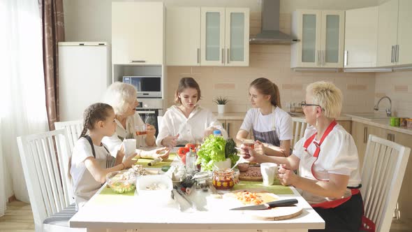 Portrait of Young Generation with Grandmothers Talking Over Cup of Tea at Home