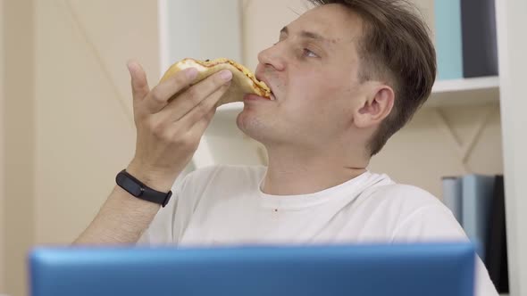 Close-up Face of Brunette Grey-eyed Man Eating Pizza and Surfing Internet