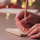 Man Writes Shopping List for Holidays in Notepad with a Pencil Under Warm Light in the Evening - VideoHive Item for Sale