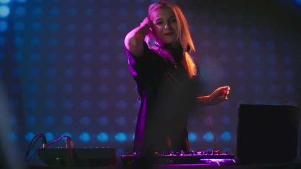 Blond Female DJ Dancing behind Mixer