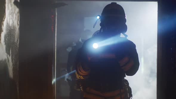 Firemen with Flashlights Walking Through Burnt Corridor