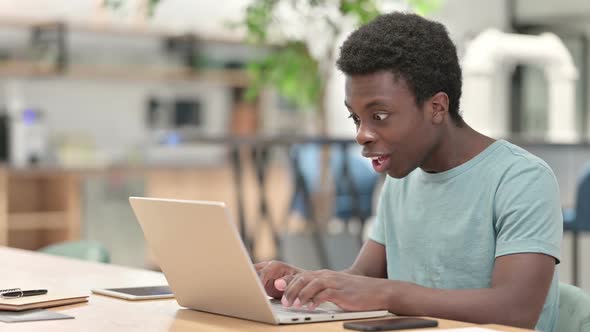 Excited Young African Man Celebrating Success on Laptop