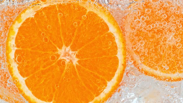 Super Slow Motion Shot of Fizzing Water with Orange Slices and Ice Cubes in Glass at 1000 Fps