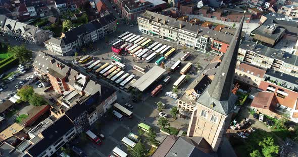 An aerial shot of busses gathering on a town square with the church dominating the view.
