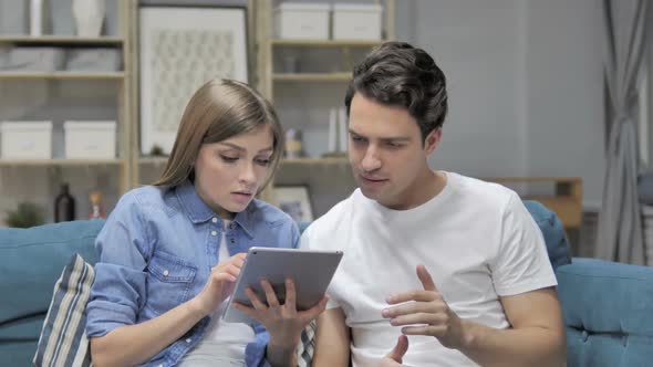 Upset Young Couple Reacting to Financial Loss While Using Tablet