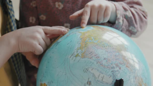 Unrecognizable Kids Using World Globe